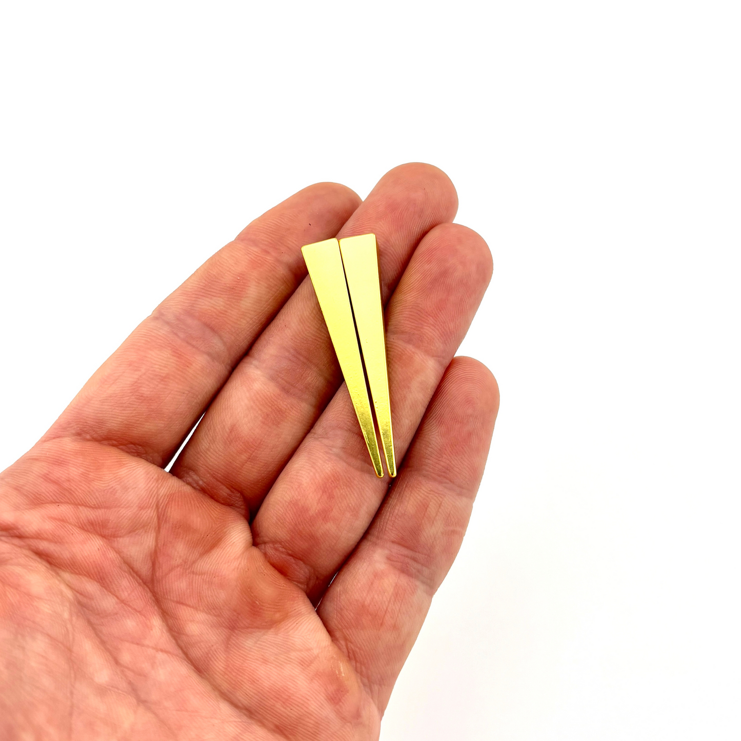 Gold-colored triangular object held in a hand against a white background